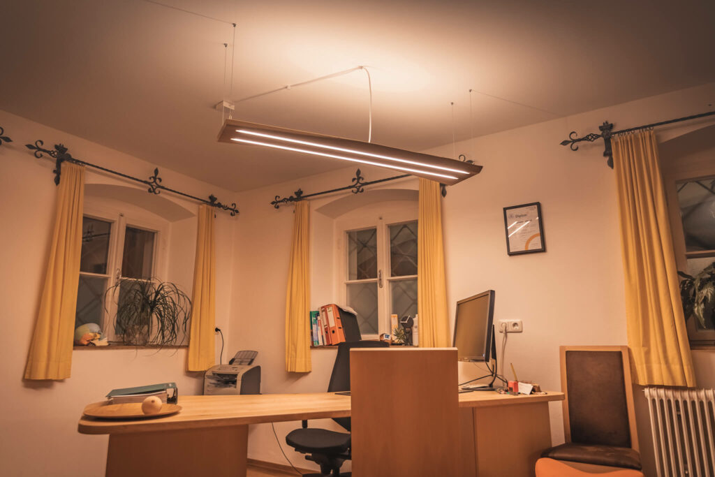 Lichten Lampe aus Eichenholz in abgehängter Variante in einem Büroraum über dem Schreibtisch